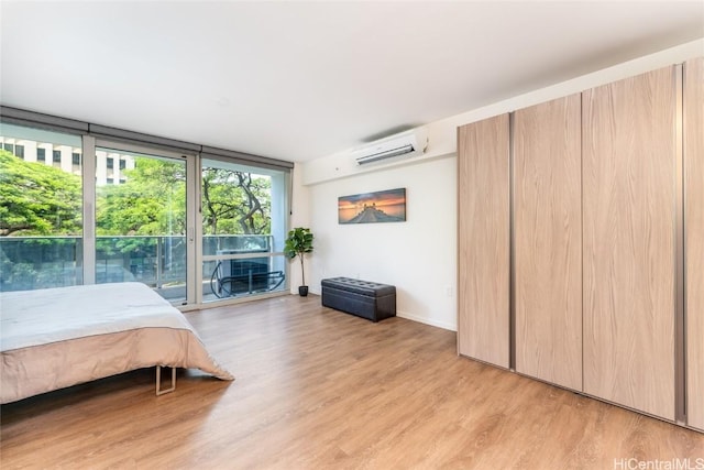 bedroom with a wall mounted AC, floor to ceiling windows, and light wood-type flooring