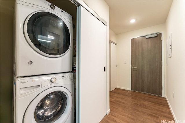 laundry room with hardwood / wood-style floors and stacked washer and clothes dryer