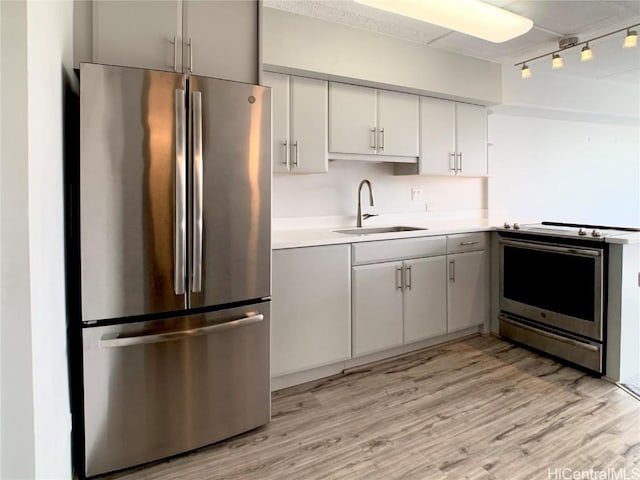 kitchen featuring white cabinetry, sink, light hardwood / wood-style floors, and appliances with stainless steel finishes