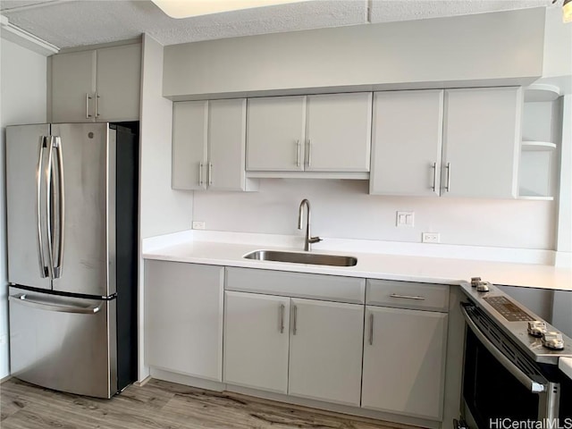 kitchen featuring a textured ceiling, sink, light wood-type flooring, and stainless steel appliances