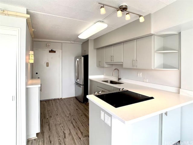 kitchen featuring kitchen peninsula, stainless steel fridge, a breakfast bar, sink, and light hardwood / wood-style flooring