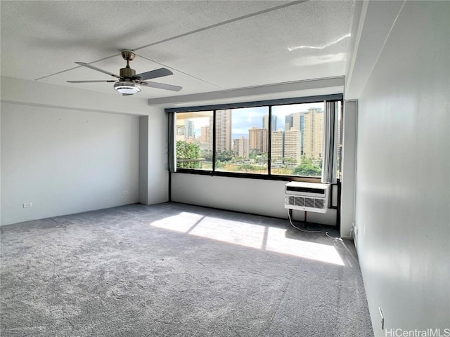 carpeted empty room featuring an AC wall unit, ceiling fan, and a textured ceiling