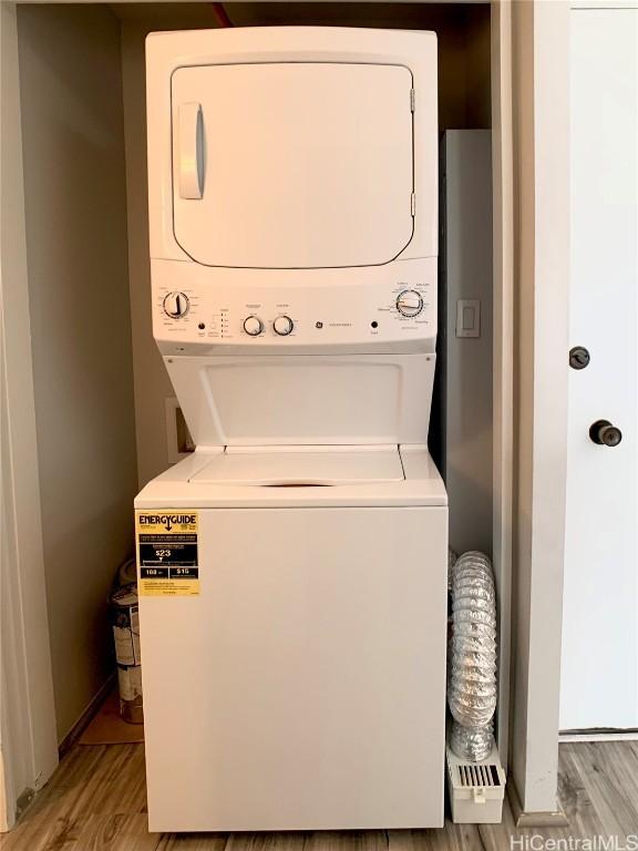 laundry area with stacked washer and dryer and light hardwood / wood-style floors