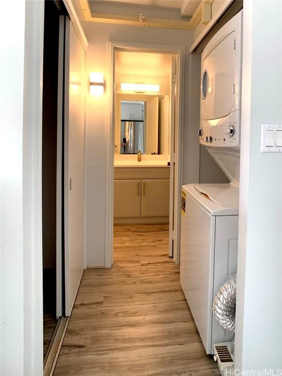 clothes washing area with light hardwood / wood-style floors and stacked washing maching and dryer