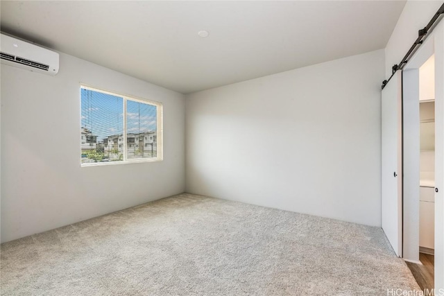 spare room featuring carpet flooring, a barn door, and a wall unit AC