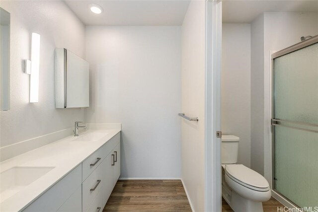 bathroom with hardwood / wood-style flooring, vanity, toilet, and walk in shower