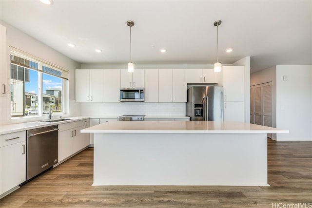 kitchen featuring appliances with stainless steel finishes, white cabinetry, a kitchen island, and pendant lighting