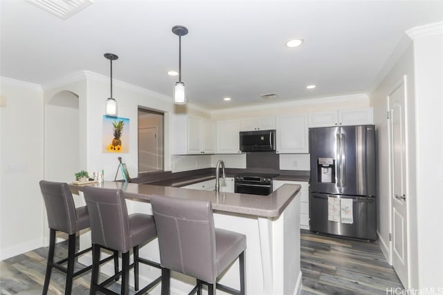 kitchen with appliances with stainless steel finishes, dark wood-type flooring, crown molding, white cabinetry, and hanging light fixtures