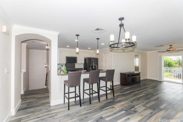 kitchen featuring black appliances, white cabinetry, dark wood-type flooring, and hanging light fixtures