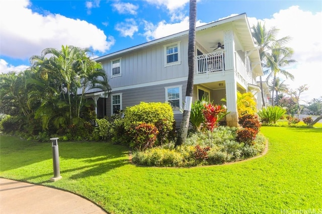 view of side of home featuring a lawn, ceiling fan, and a balcony