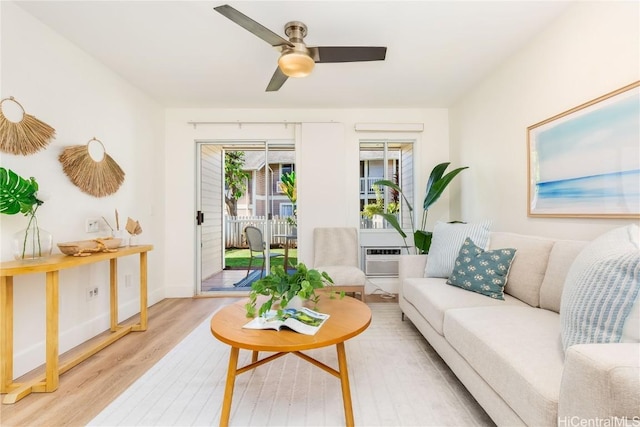 living room featuring ceiling fan, light hardwood / wood-style floors, and a wall mounted air conditioner