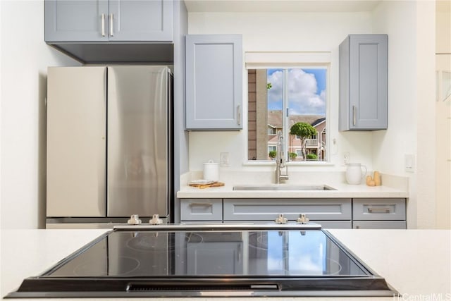 kitchen featuring gray cabinets, stainless steel fridge, sink, and black electric cooktop