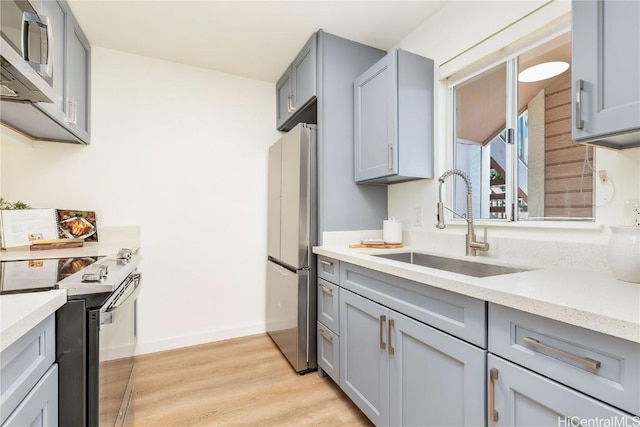 kitchen featuring gray cabinets, stainless steel appliances, light hardwood / wood-style flooring, and sink