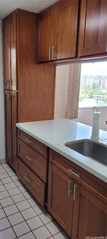 kitchen featuring light tile patterned flooring, sink, and a textured ceiling