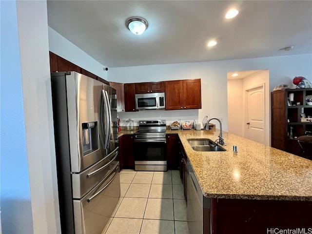 kitchen with kitchen peninsula, light stone counters, stainless steel appliances, sink, and light tile patterned floors