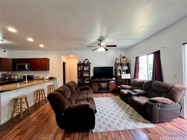 living room featuring hardwood / wood-style flooring, ceiling fan, and sink