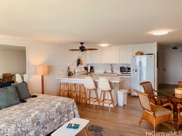 bedroom with ceiling fan, sink, light hardwood / wood-style floors, and white refrigerator with ice dispenser