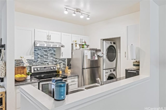 kitchen with white cabinets, appliances with stainless steel finishes, tasteful backsplash, and stacked washer / dryer