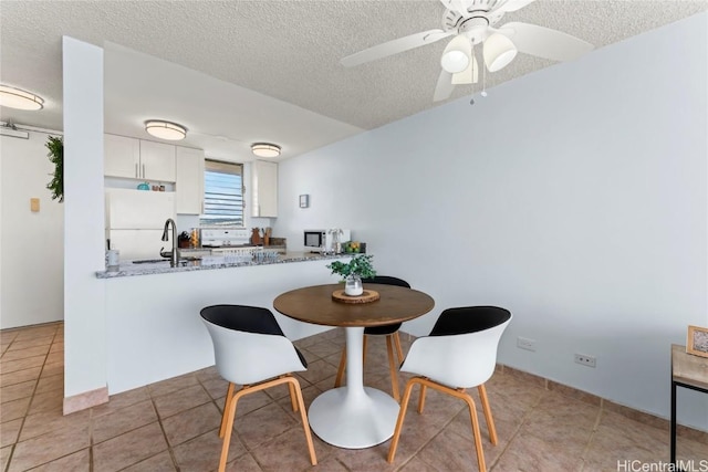 dining space with ceiling fan, light tile patterned flooring, sink, and a textured ceiling