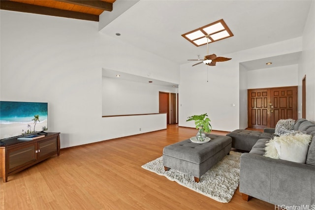 living room featuring beam ceiling, ceiling fan, high vaulted ceiling, and light wood-type flooring