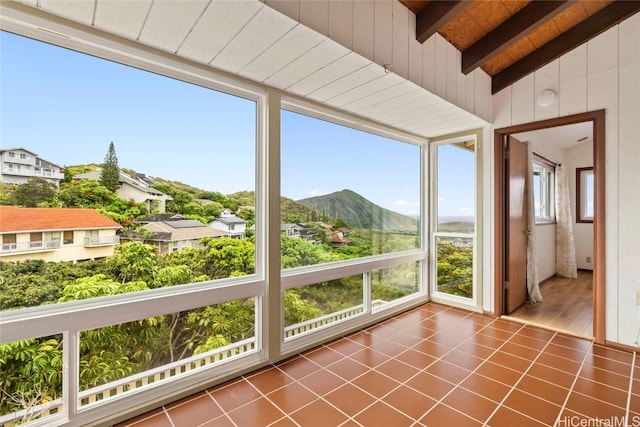 unfurnished sunroom featuring vaulted ceiling with beams, a mountain view, and wood ceiling