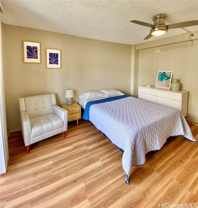 bedroom featuring ceiling fan, light wood-type flooring, and a textured ceiling