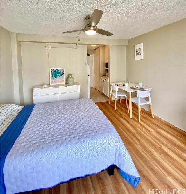 bedroom with a textured ceiling, light hardwood / wood-style floors, and ceiling fan