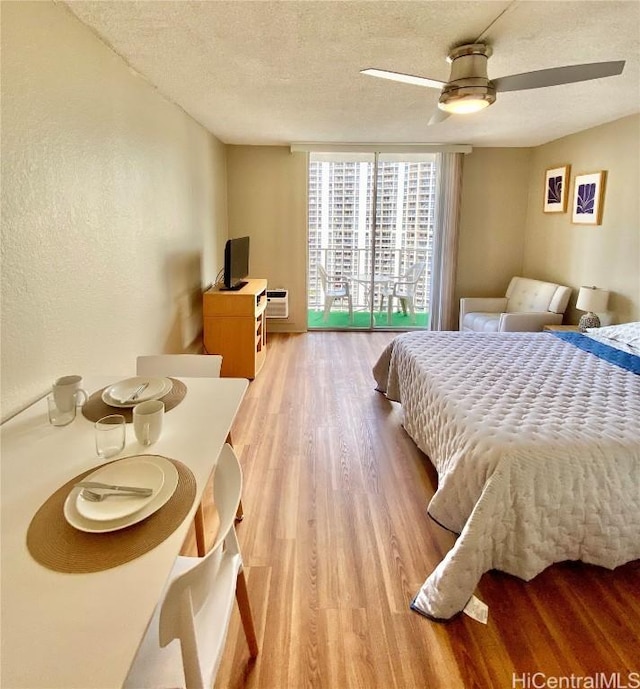 bedroom featuring ceiling fan, light hardwood / wood-style floors, and a textured ceiling