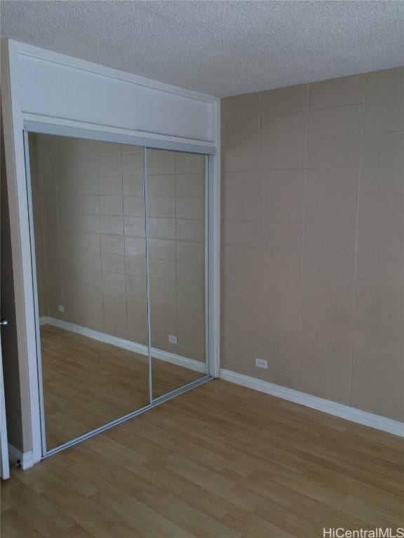 unfurnished bedroom with light hardwood / wood-style floors, a textured ceiling, and a closet