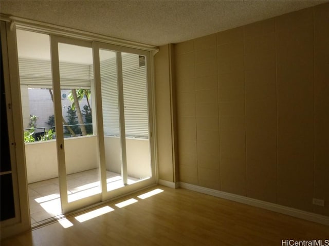 unfurnished room with light hardwood / wood-style flooring and a textured ceiling