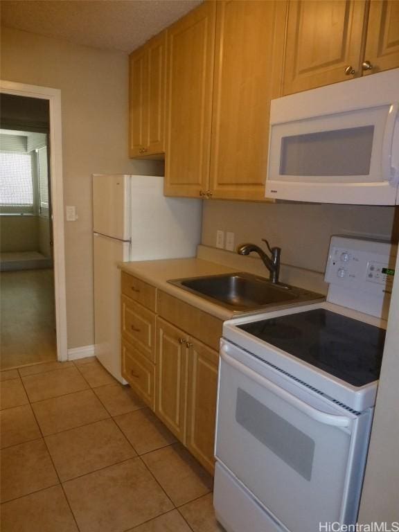 kitchen with light tile patterned floors, white appliances, light brown cabinetry, and sink