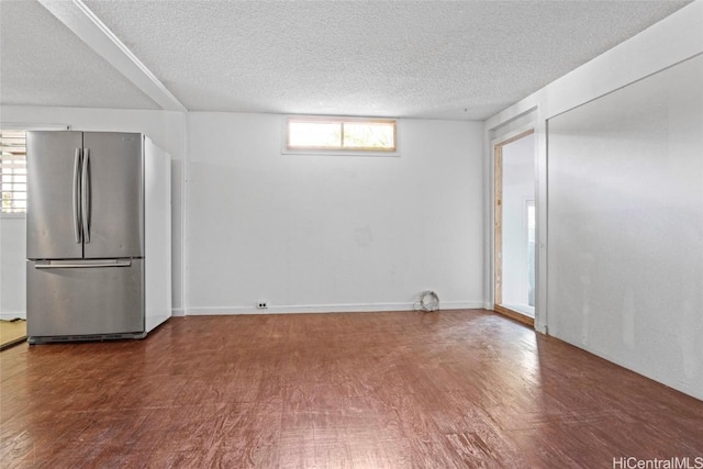 interior space featuring a textured ceiling, hardwood / wood-style flooring, and stainless steel fridge