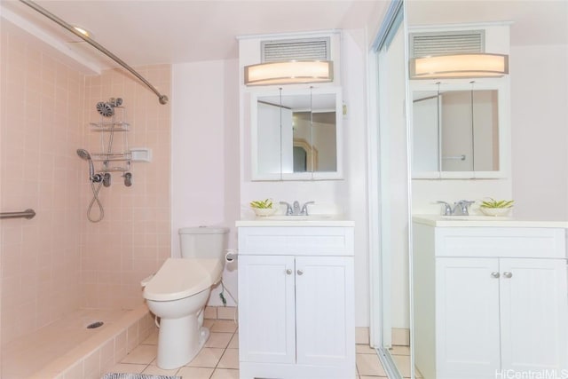 bathroom with tile patterned flooring, vanity, toilet, and tiled shower