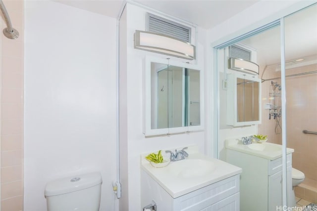 bathroom with vanity, toilet, and tiled shower