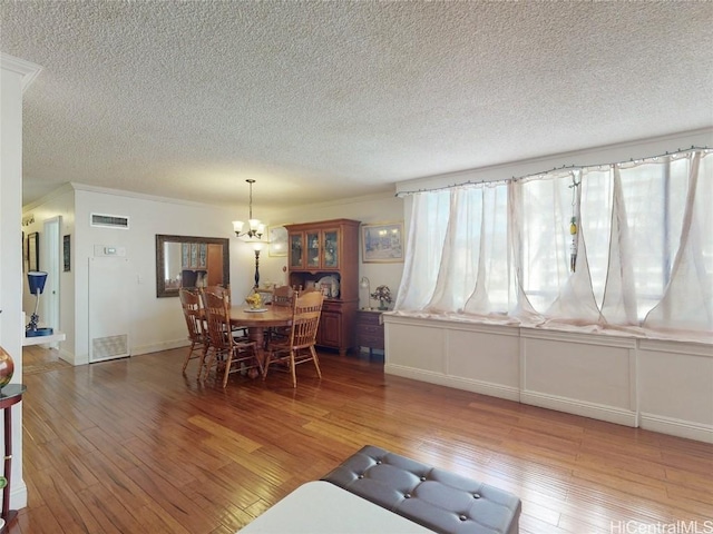 dining room featuring a textured ceiling, a chandelier, and dark hardwood / wood-style floors