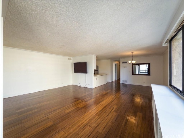 unfurnished living room with a notable chandelier, dark hardwood / wood-style floors, and a textured ceiling