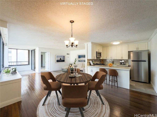 dining area with dark hardwood / wood-style flooring, a textured ceiling, and a notable chandelier