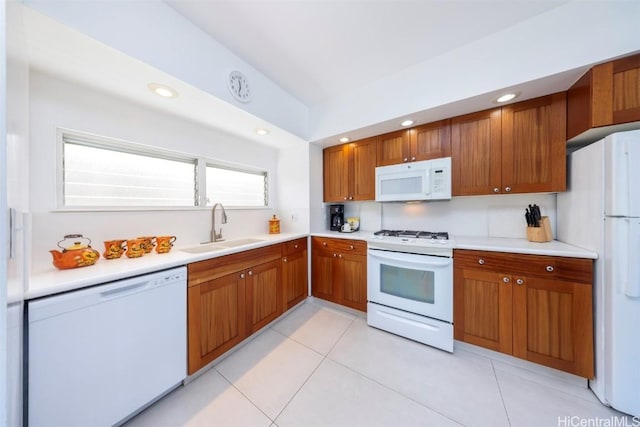 kitchen with a sink, white appliances, brown cabinetry, and light countertops