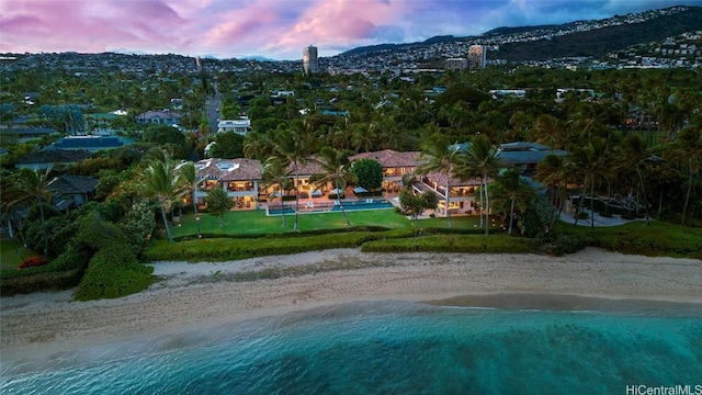 aerial view at dusk featuring a water view and a view of the beach