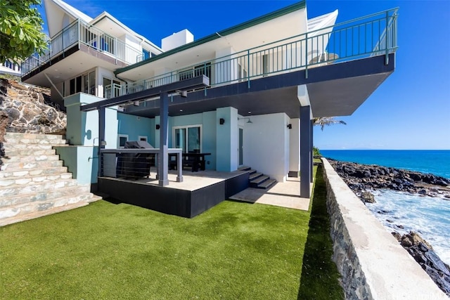 rear view of property with a yard, a water view, and a patio area