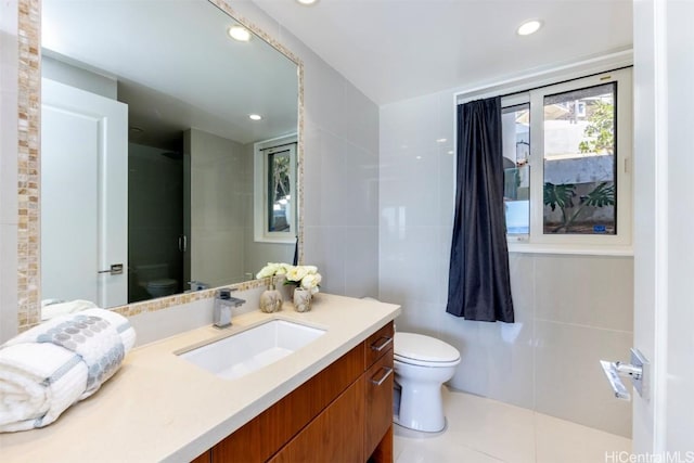 bathroom with tile patterned flooring, vanity, toilet, and tile walls