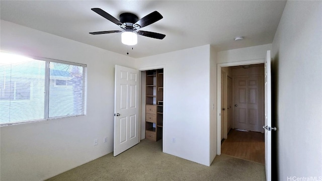 unfurnished bedroom with light colored carpet, a closet, and ceiling fan