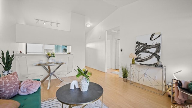 interior space featuring vaulted ceiling, rail lighting, and light hardwood / wood-style floors