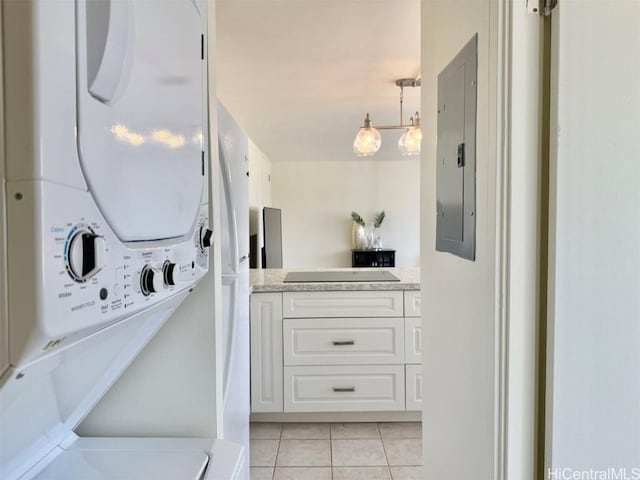 clothes washing area with stacked washer and dryer, electric panel, and light tile patterned flooring