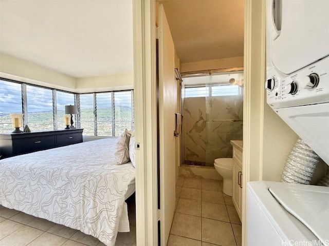 bedroom with stacked washer / dryer, multiple windows, and light tile patterned flooring