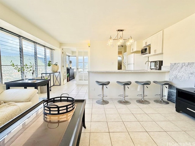 kitchen with light countertops, stainless steel microwave, a kitchen breakfast bar, and light tile patterned floors