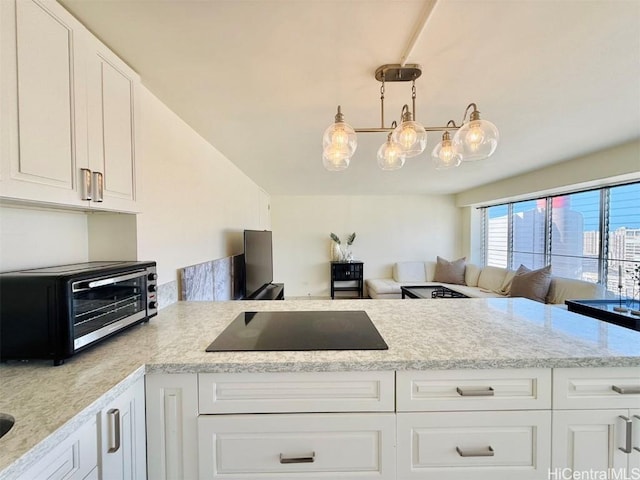 kitchen featuring a toaster, black electric stovetop, hanging light fixtures, open floor plan, and white cabinetry