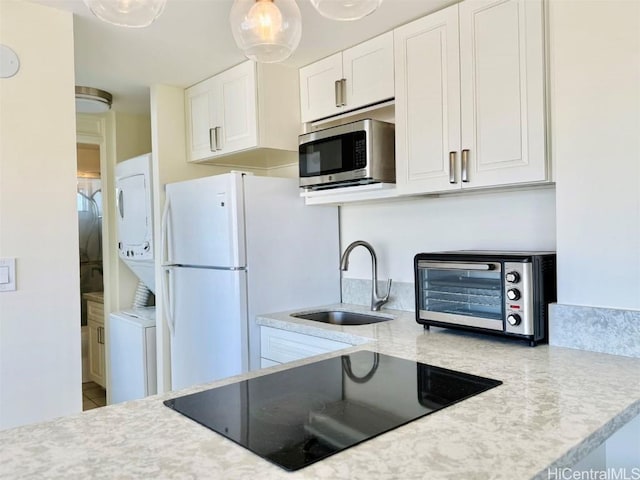 kitchen with a toaster, light countertops, stainless steel microwave, a sink, and black electric cooktop