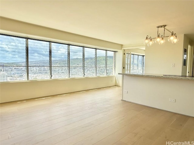 unfurnished room featuring light wood-style flooring and a notable chandelier