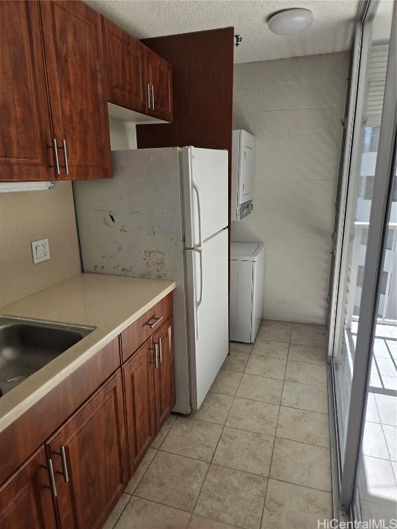 kitchen featuring light tile patterned floors, a textured ceiling, washer / clothes dryer, and white refrigerator